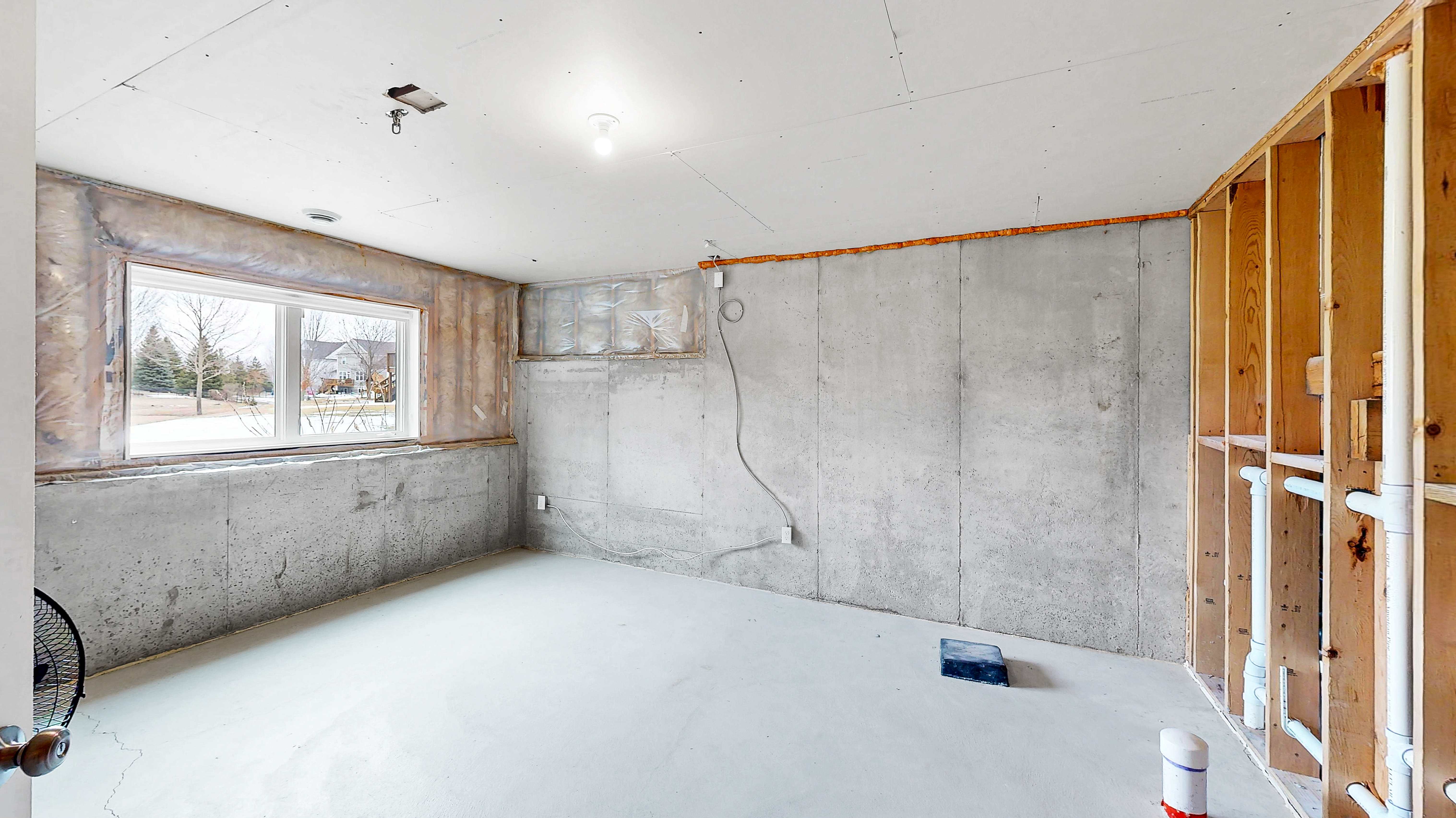 Unfinished lower level room with plumbing rough-in for future bedroom and bath