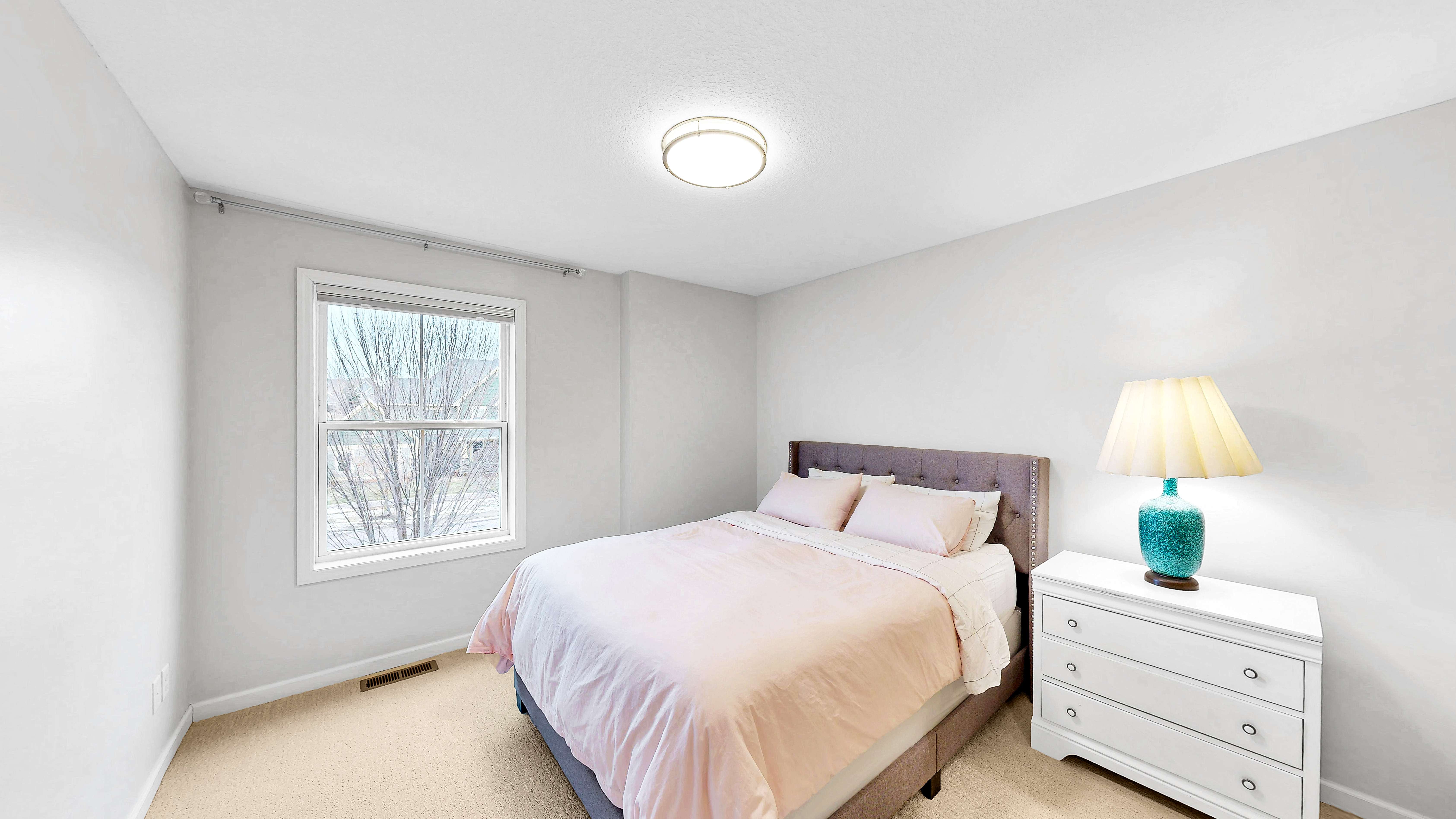 Bedroom with pink bedding and neighborhood window views