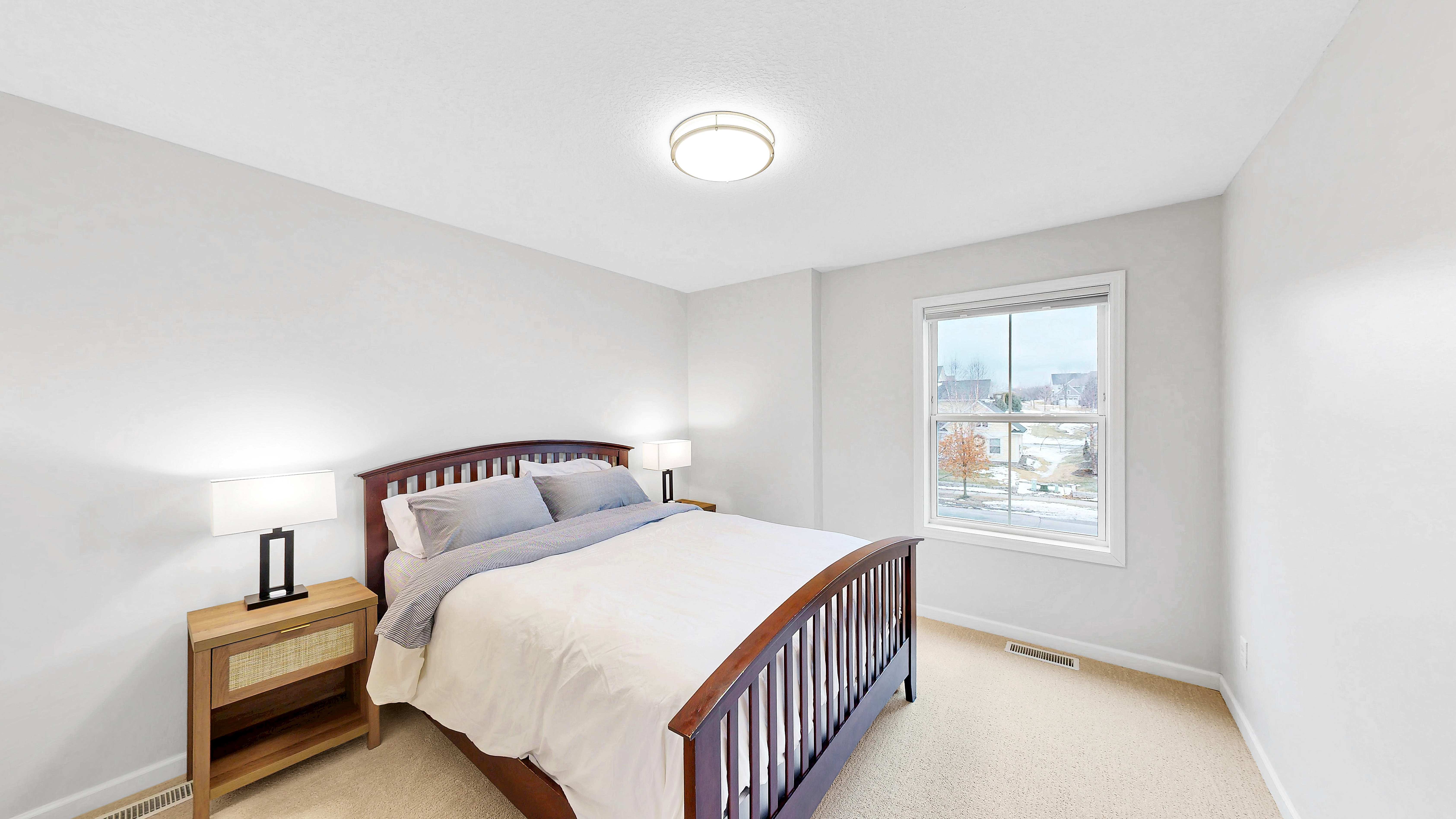 Guest bedroom with wood bed frame and neighborhood views