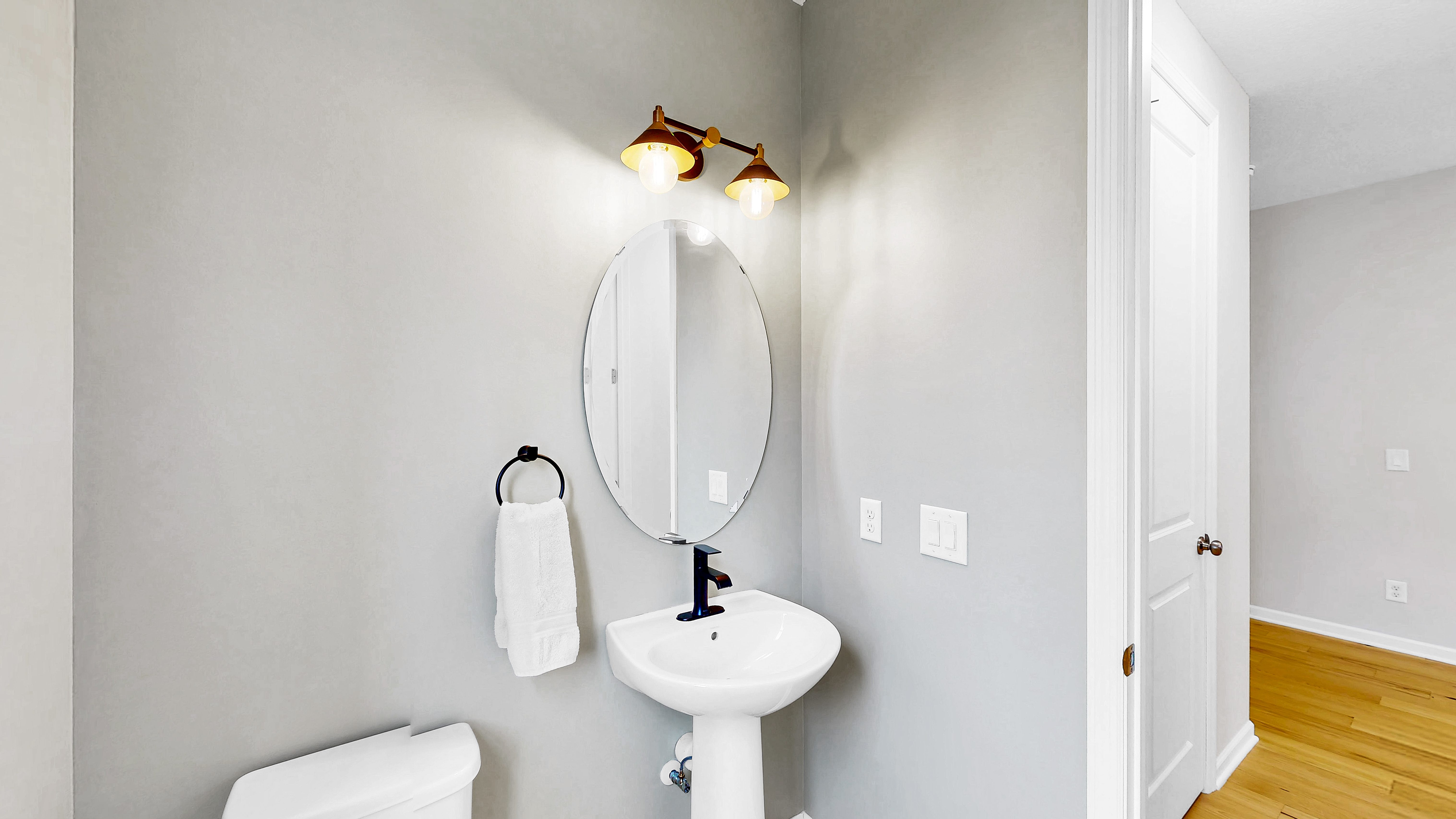 Main level powder room with pedestal sink and oval mirror