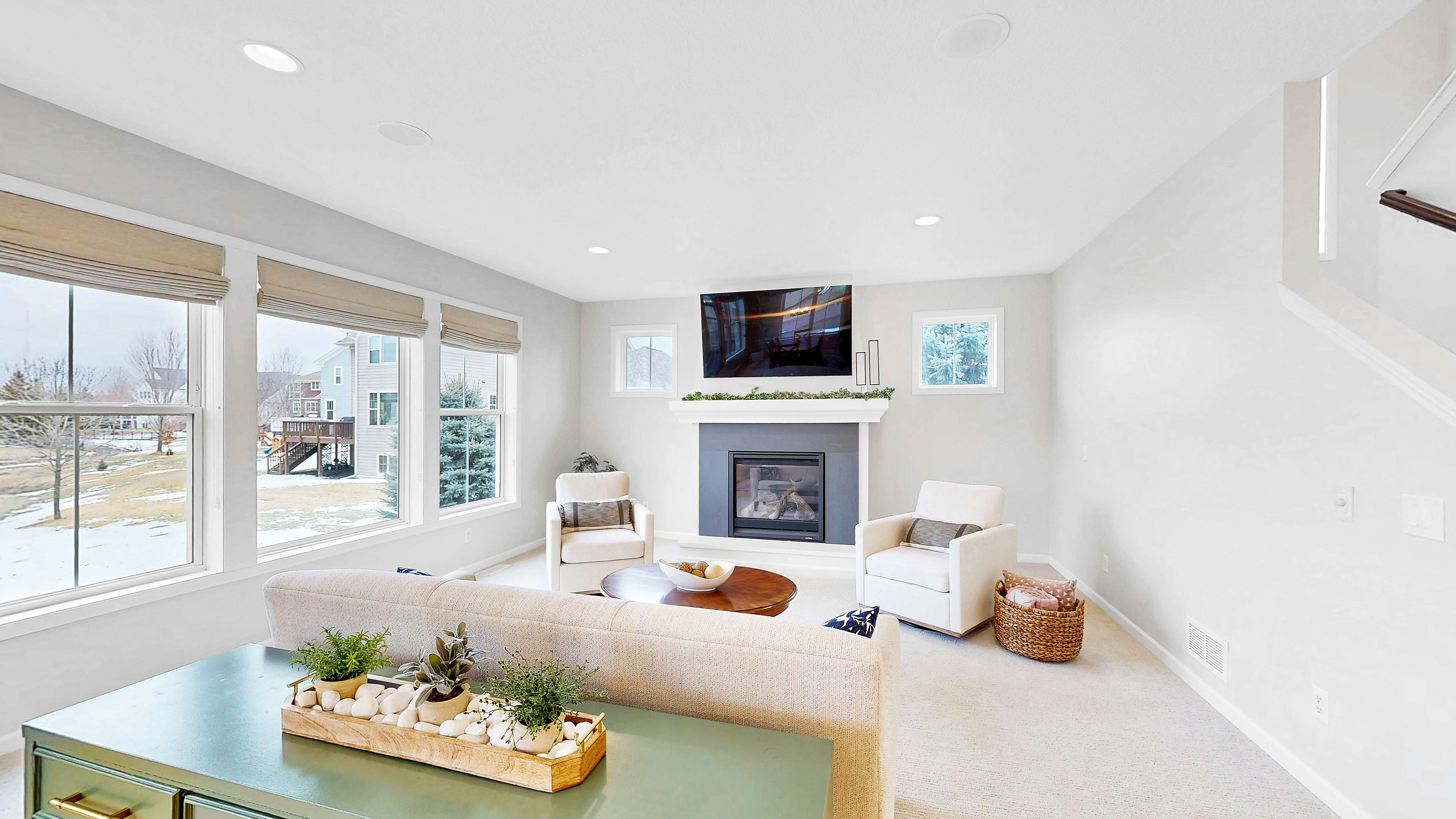 Living room with gas fireplace, large windows overlooking green space