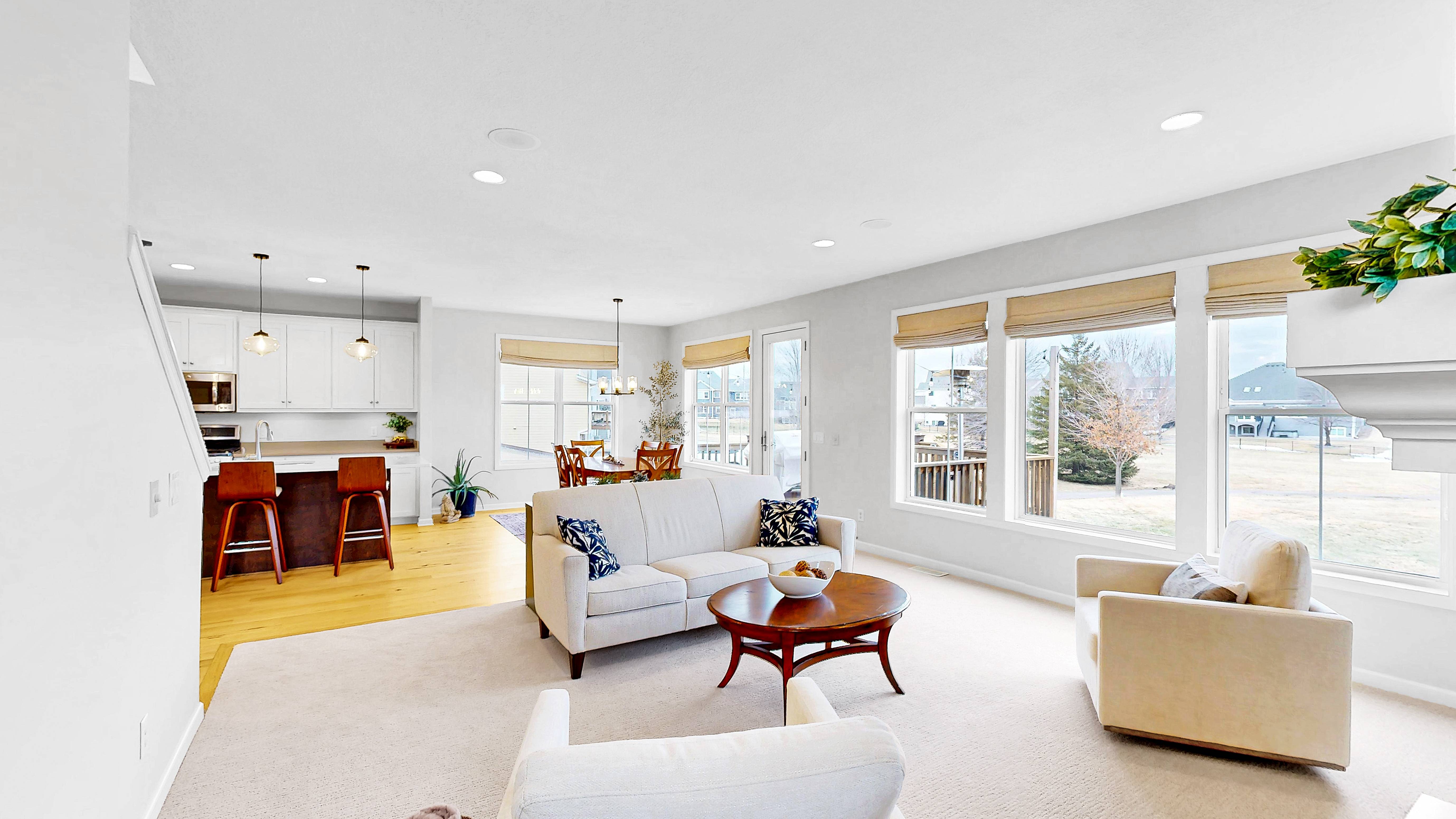 Open concept living area flowing into kitchen with large windows and natural light